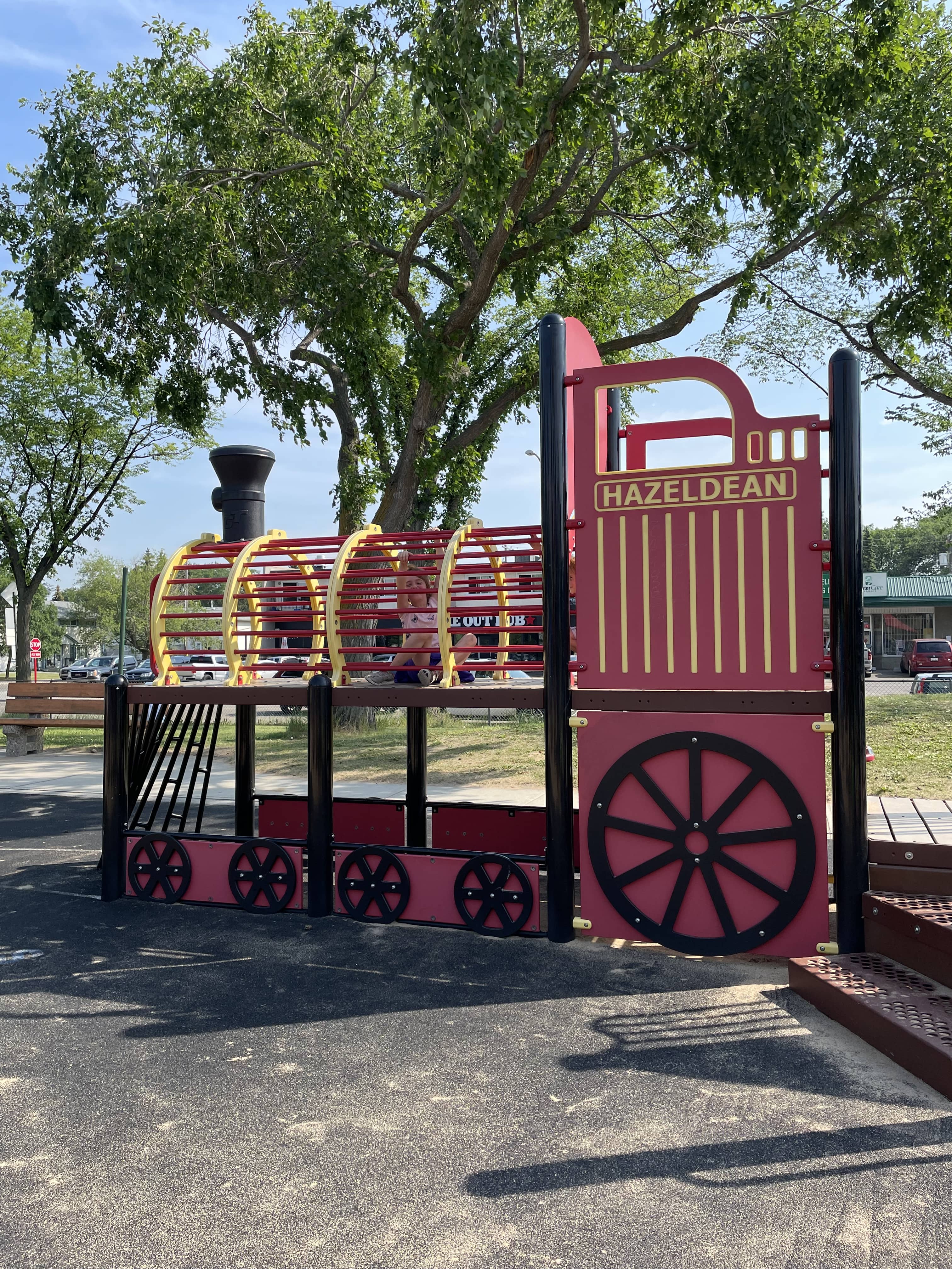 Hazeldean Park playground equipment in Edmonton, AB with paved trail through playground