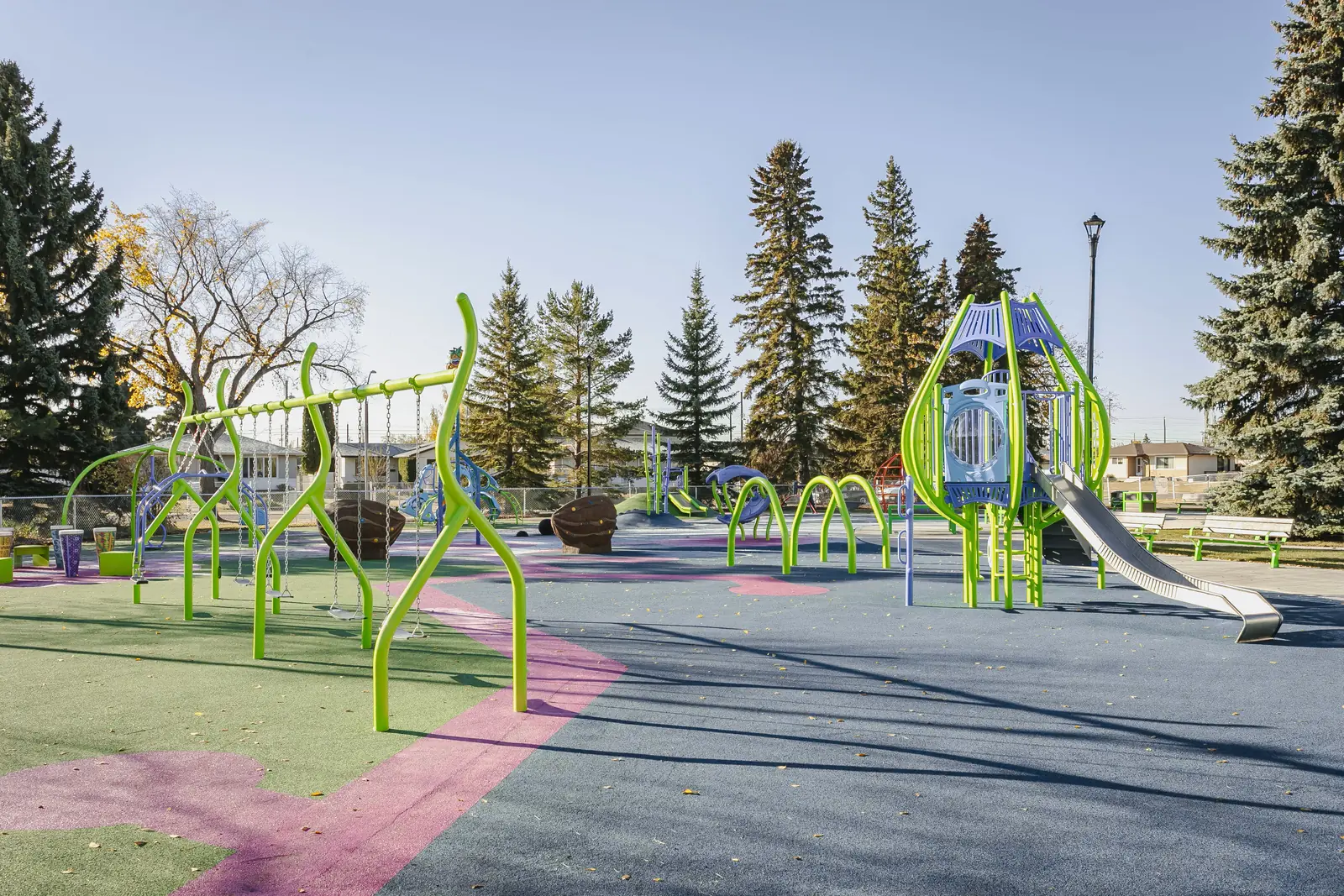 Lime-green swing frame with curving legs, arched hoops and a lime tower with a stainless steel slide