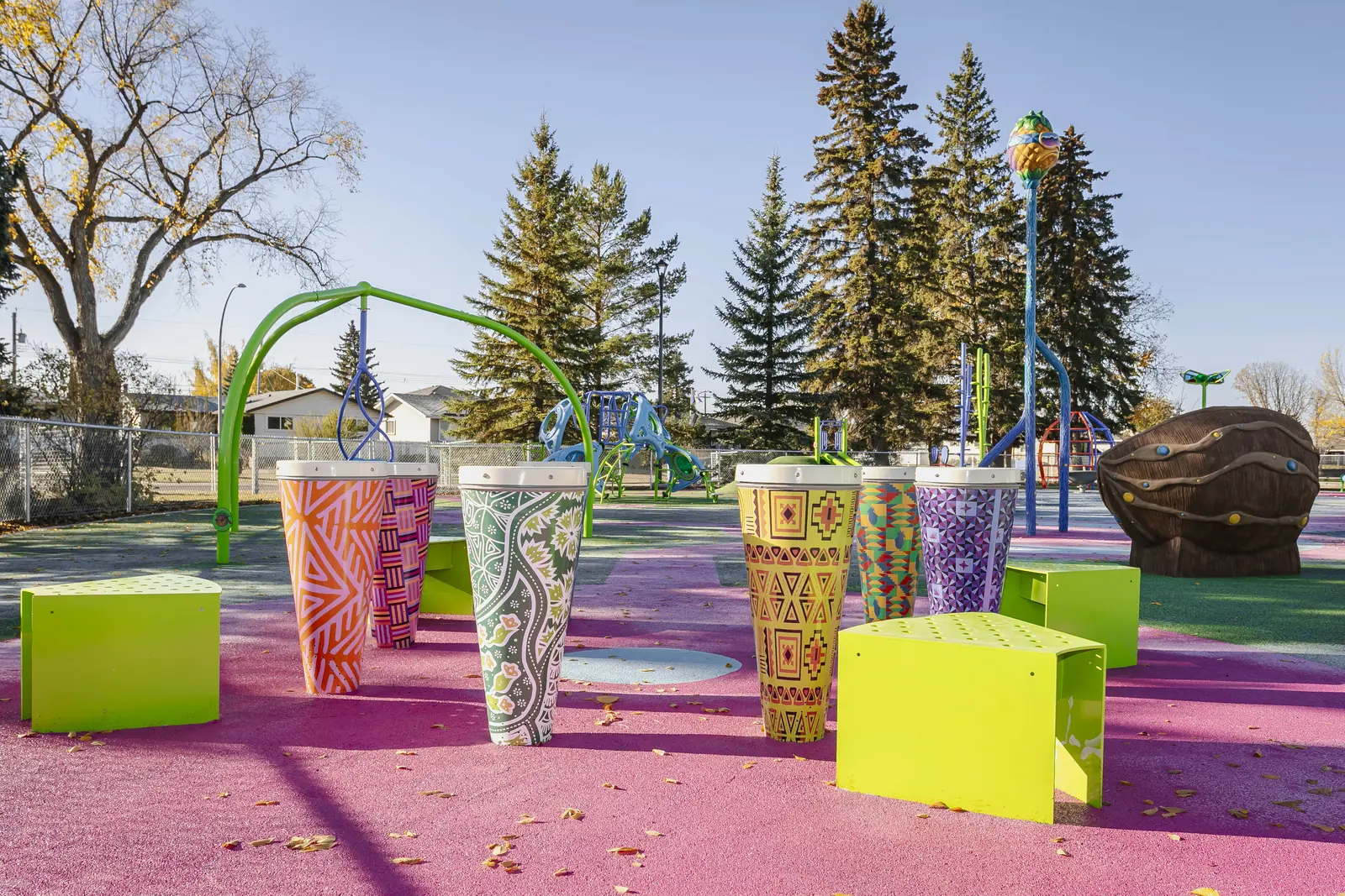 Drum circle: tall drums wrapped in bright patterned artwork, with lime-green cube seats on pink rubber