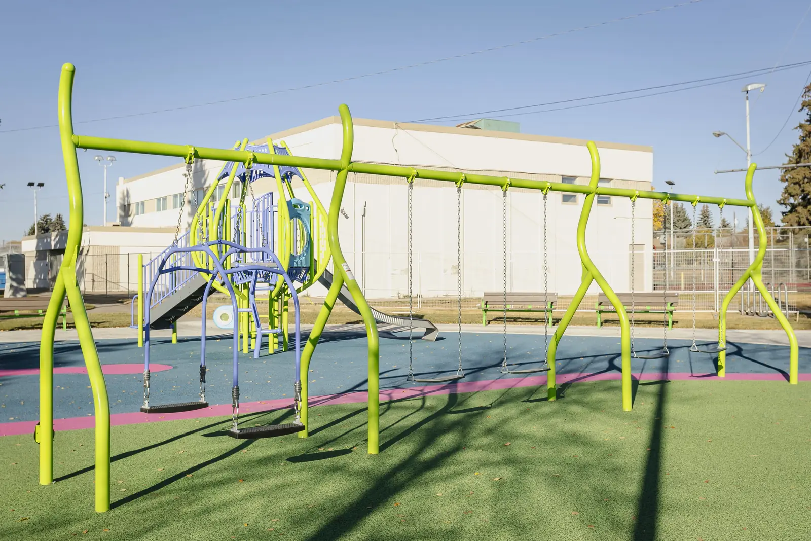 Full swing frame with lime curving legs: arched belt swings and a row of standard swings, the tower behind