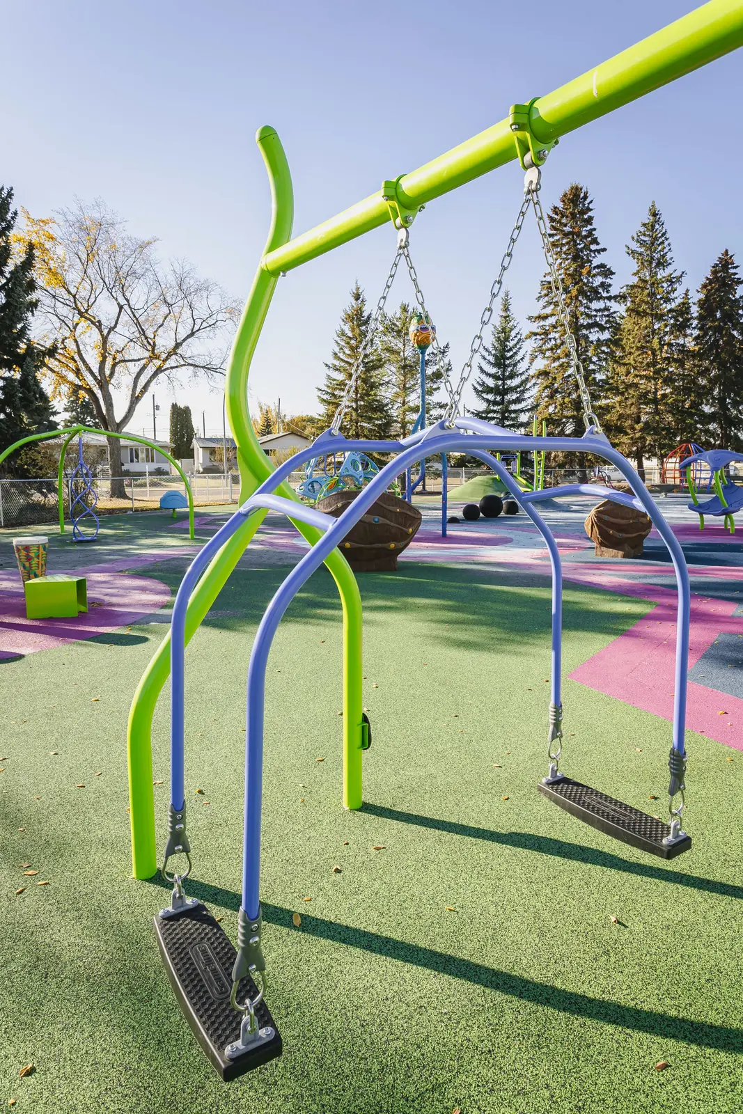2 belt seats hung from blue arches on the lime-green swing frame, over green rubber