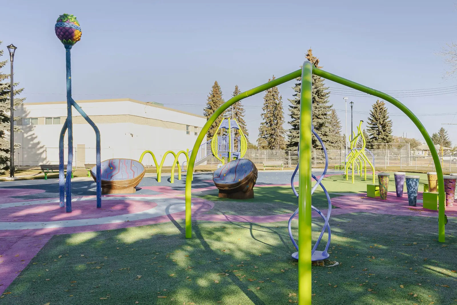 Lime arch with a hanging twisted climber, seed-pod seats and the drum circle behind