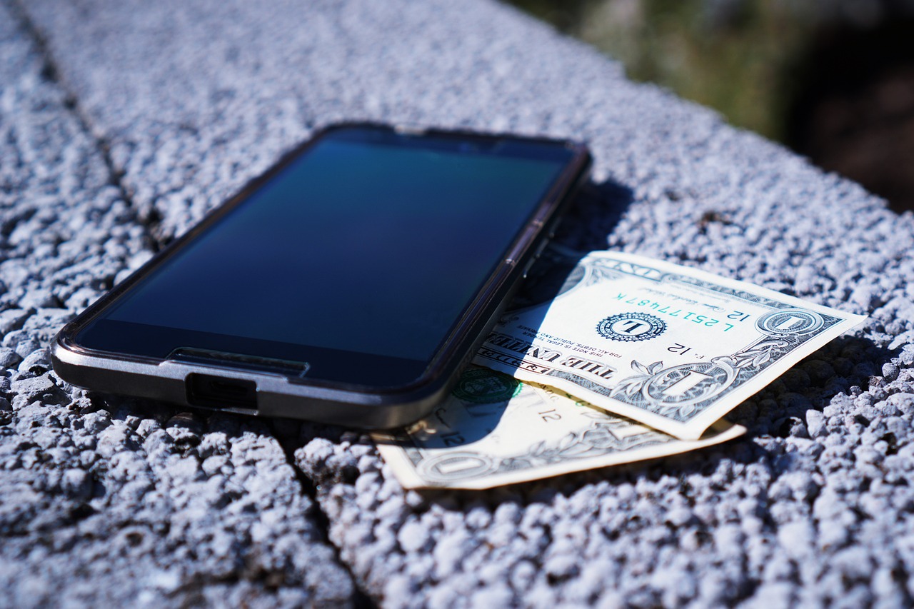 mobile phone on top of two one dollar bills