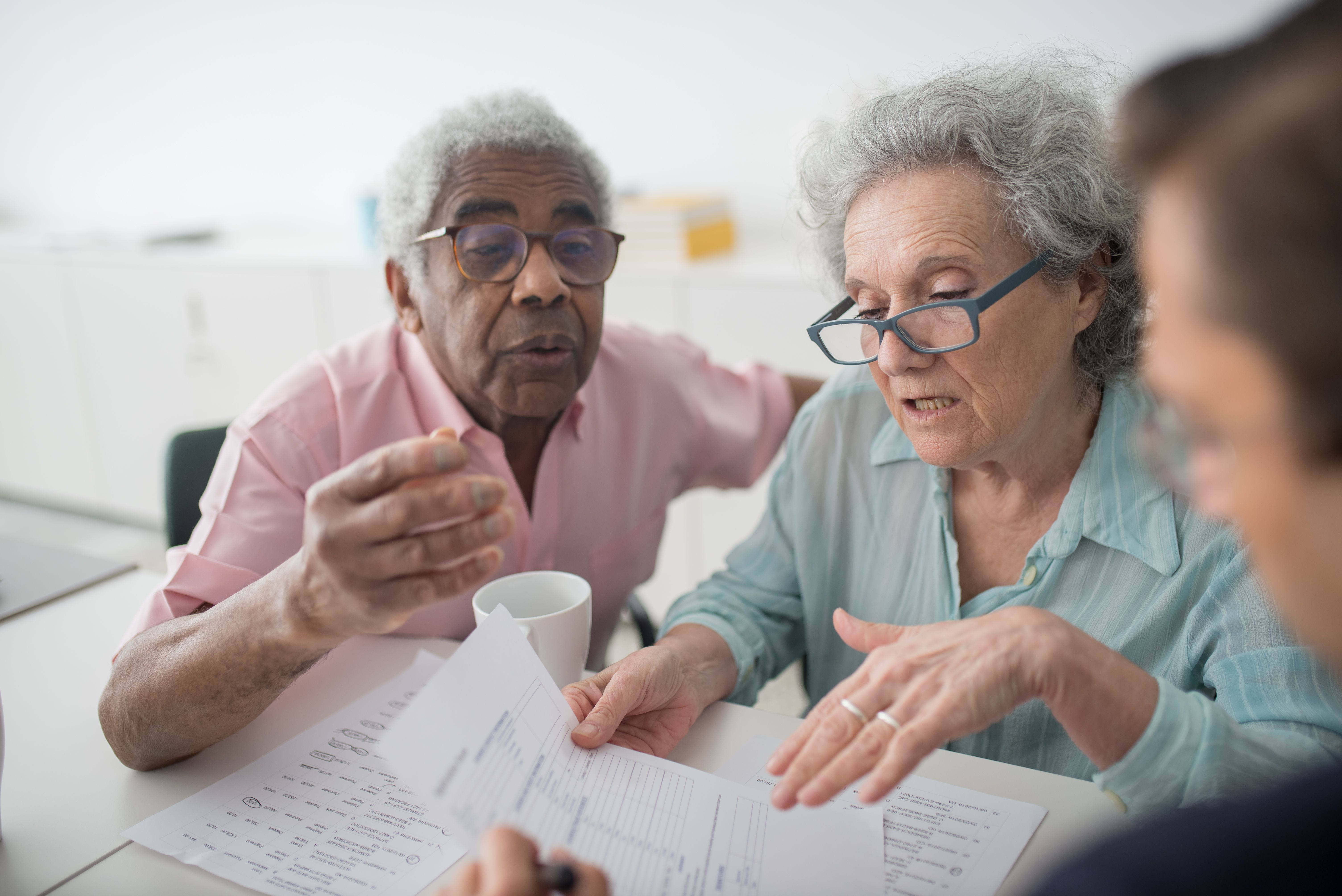 An older couple discussing a document with an advisor across a table.