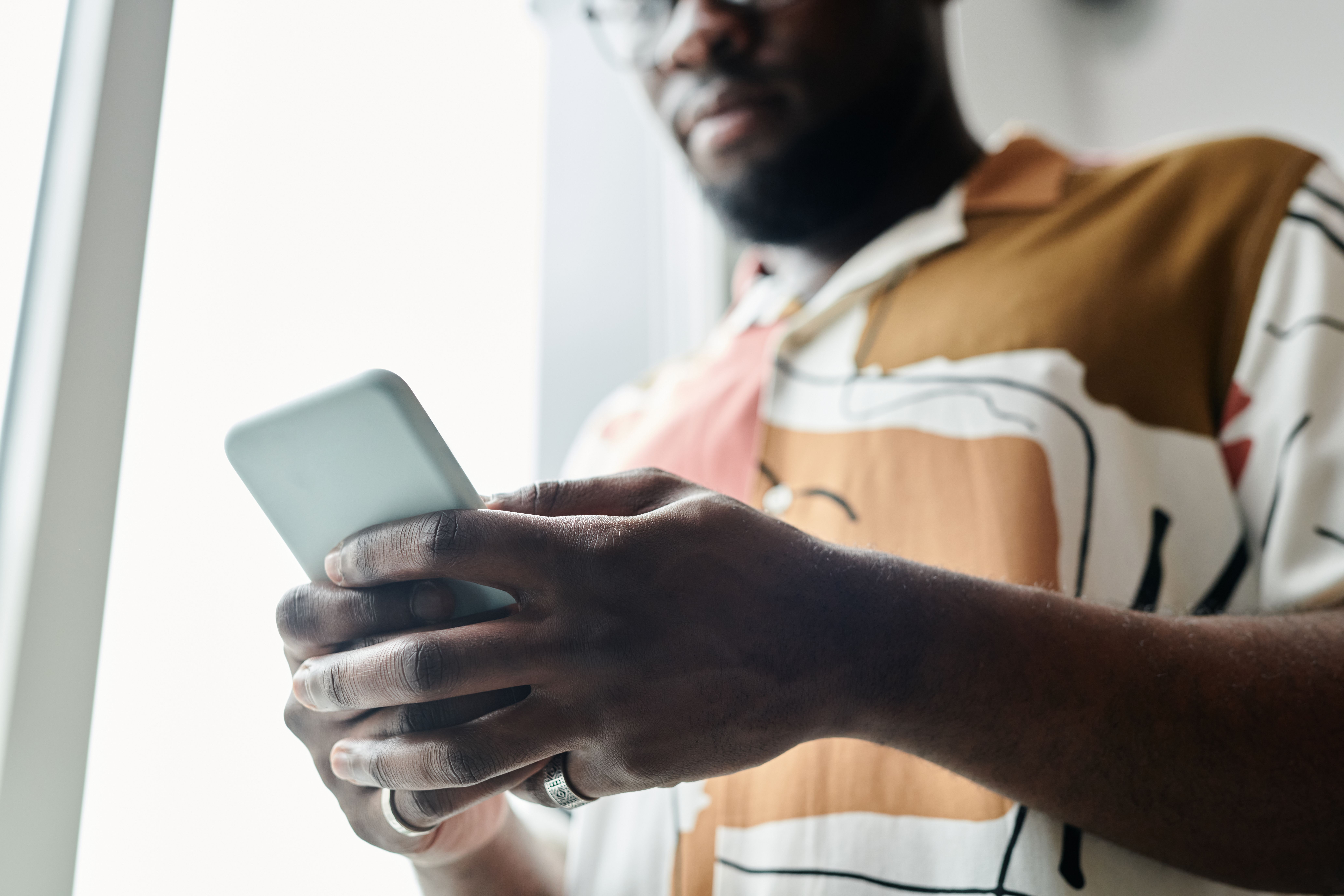Photo of a man in a patterned short-sleeve shirt checking a cash advance app on his smartphone.