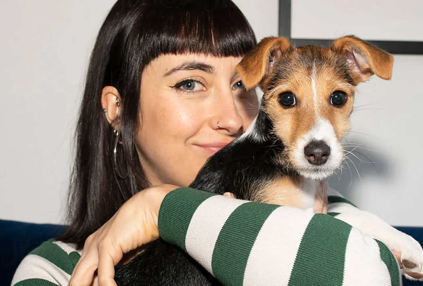 A woman smiling holding up her small dog.