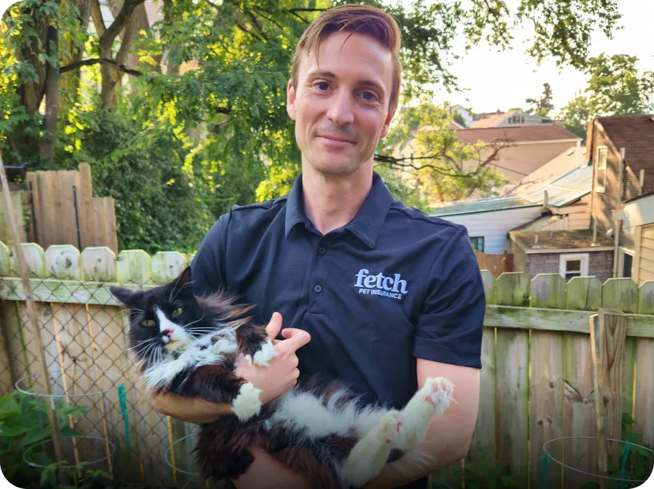 A Fetch employee holding their cat outside.