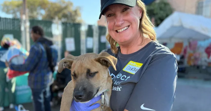 A Fetch shelter rep holding up a cute dog.