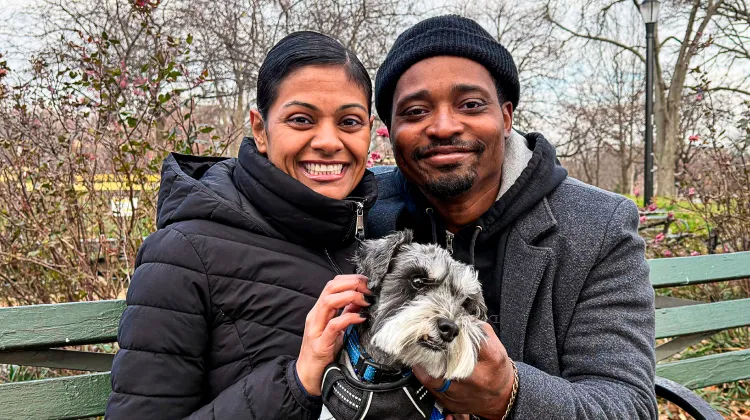 Guinness and pet parents outside sitting on a bench.