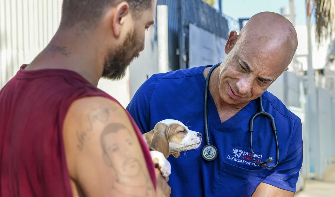 Dr. Kwane Stewart, veterinarian and co-founder of Project Street Vet, shown caring for a dog outside.