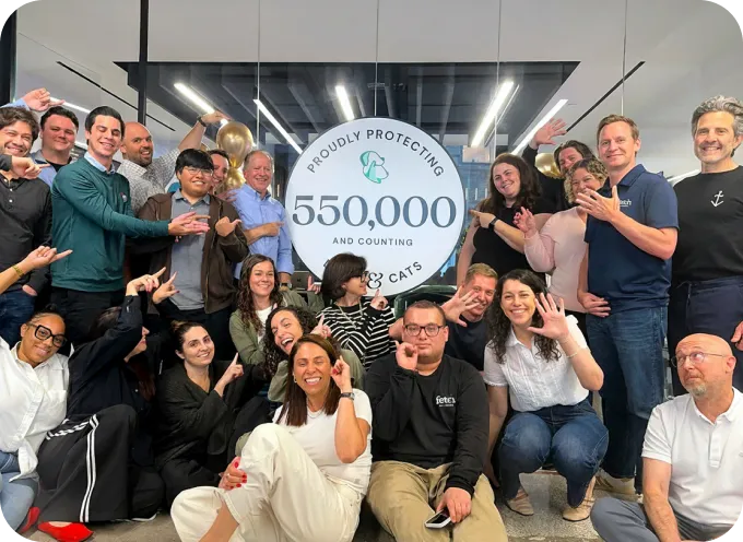 Several memebers of the Fetch team in front of a sign that says "Protecting over 500,000 Dogs & Cats".