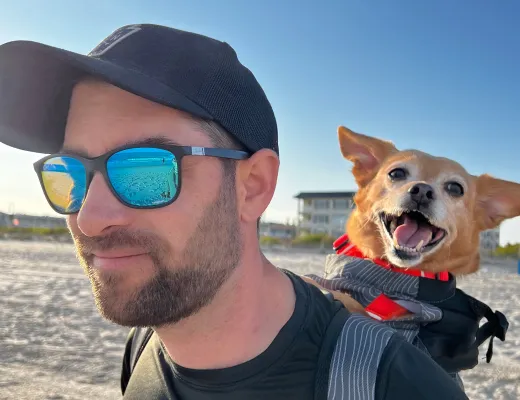 A Fetch employee walking with their dog in a backpack.