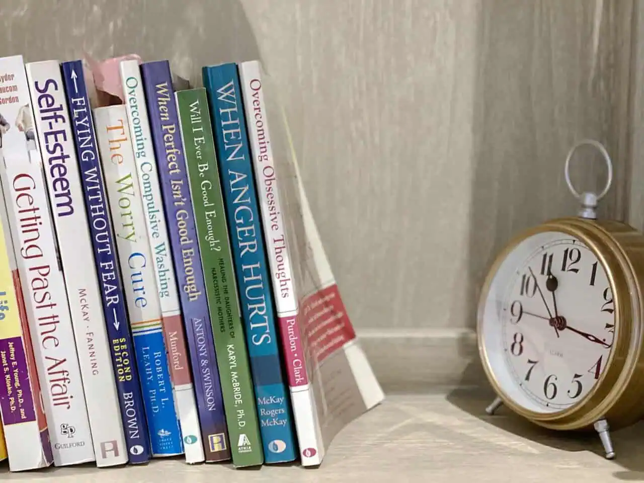 books on the shelf of psychologist office, with clock