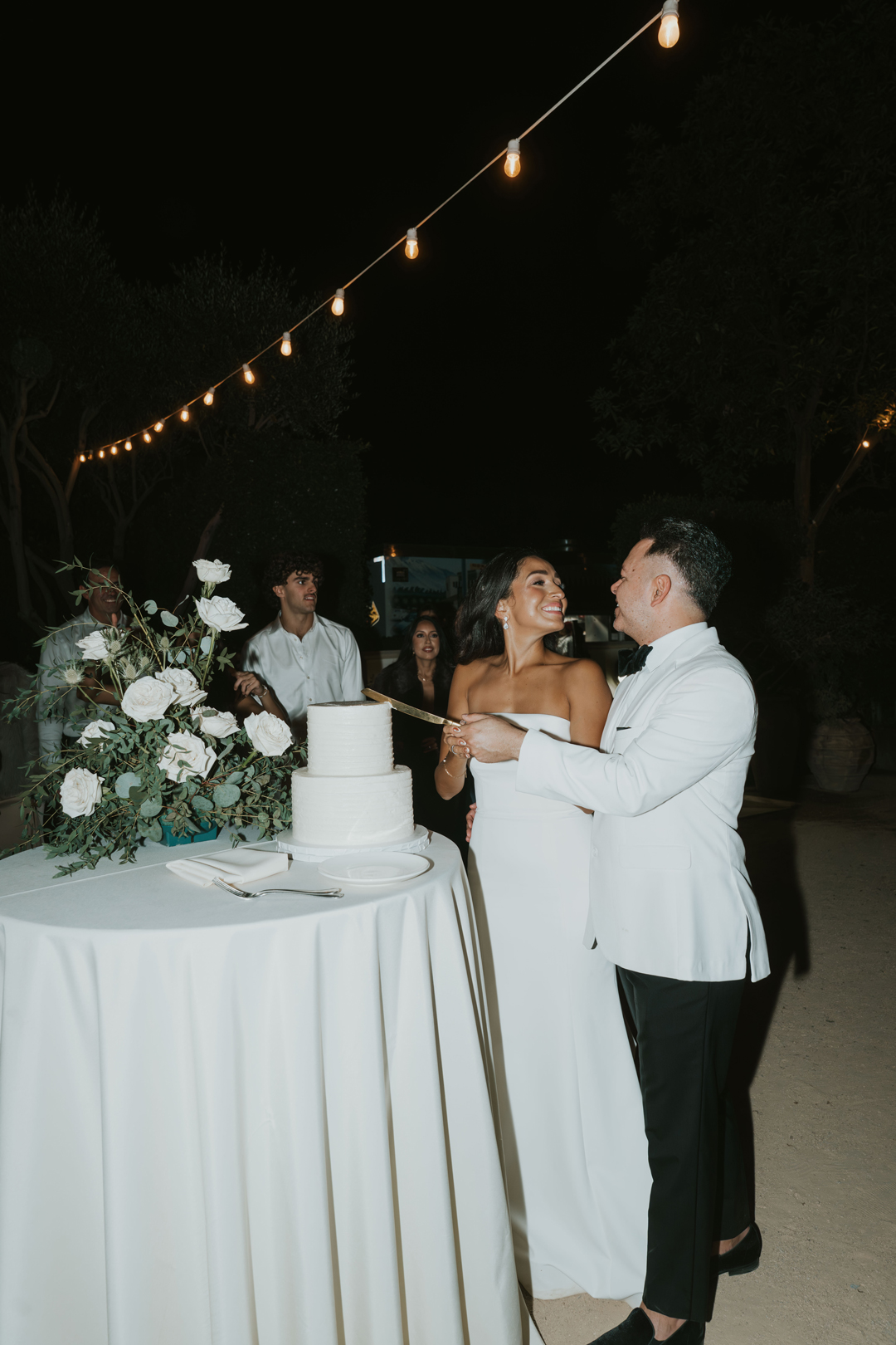 Bride and groom smile as they cut into their two-tiered wedding cake.