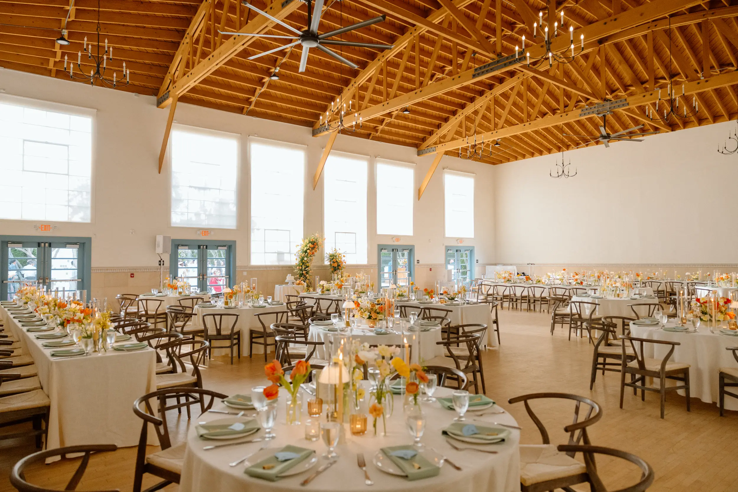 Tangerine florals top wedding reception tables inside Grand Central at Grand Gimeno.
