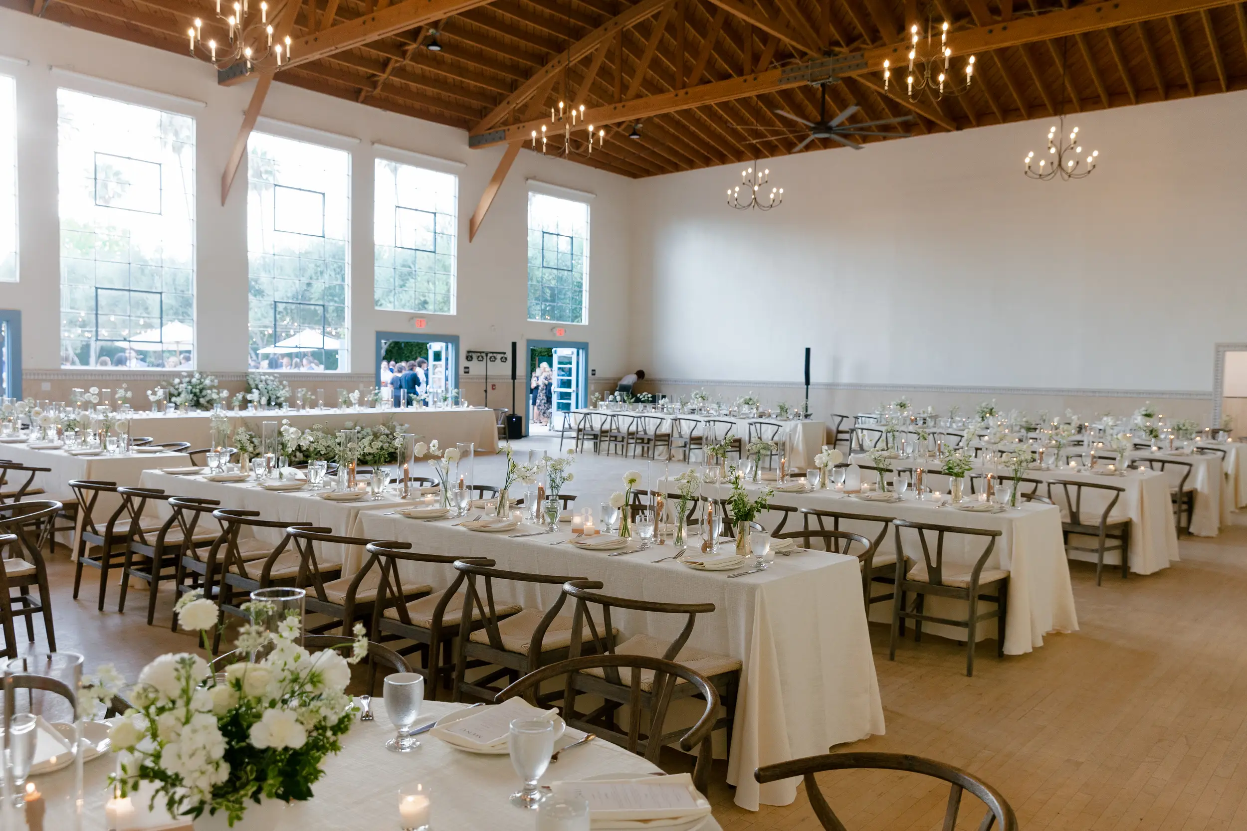 Indoor wedding reception with taupe candlesticks and white floral arrangements.