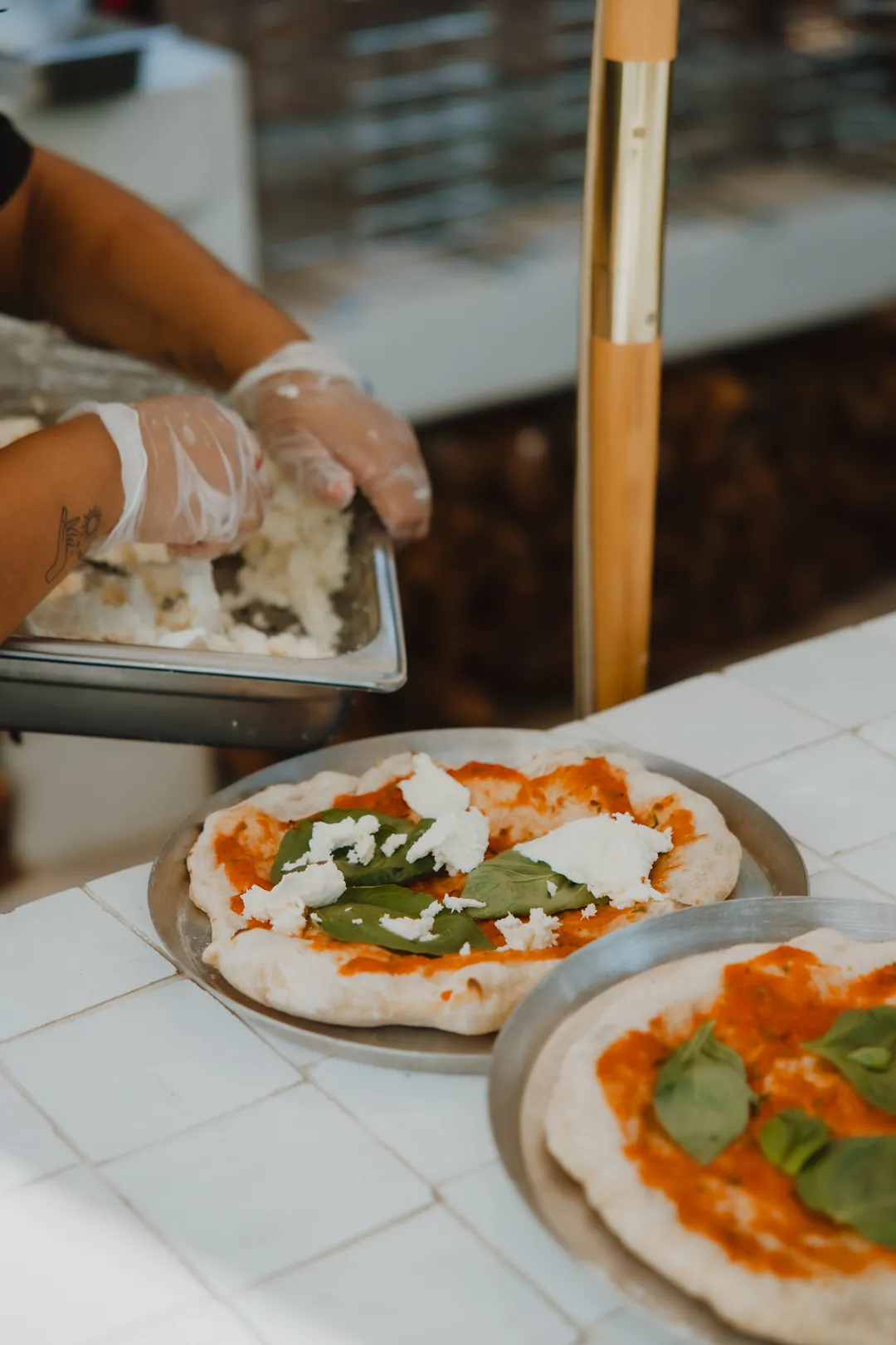 Chef adding a topping to a freshly prepared pizza