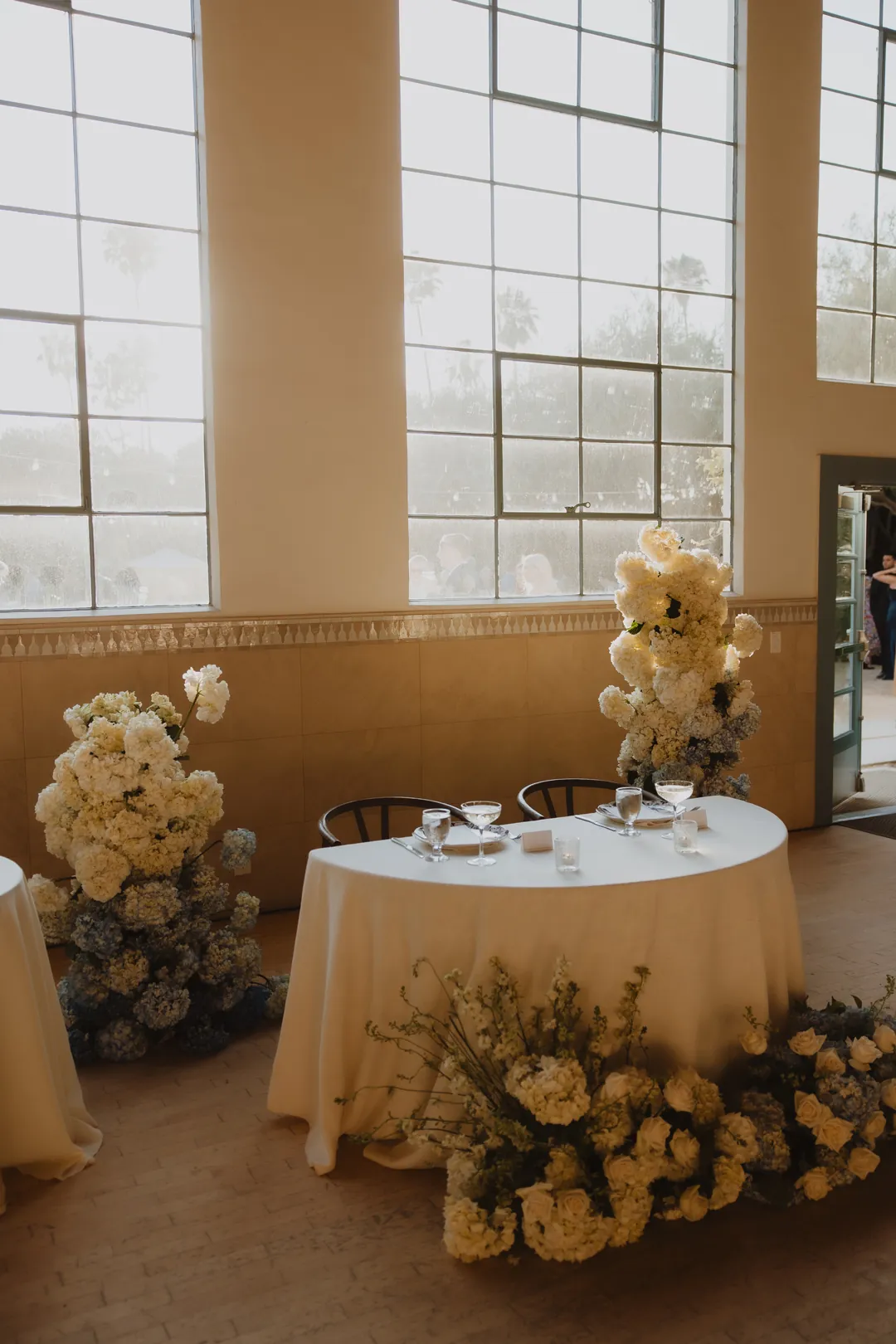 Sweetheart table beneath tall reception windows