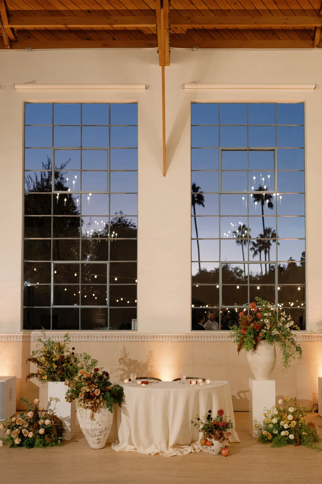 Sweetheart table beneath tall windows at dusk