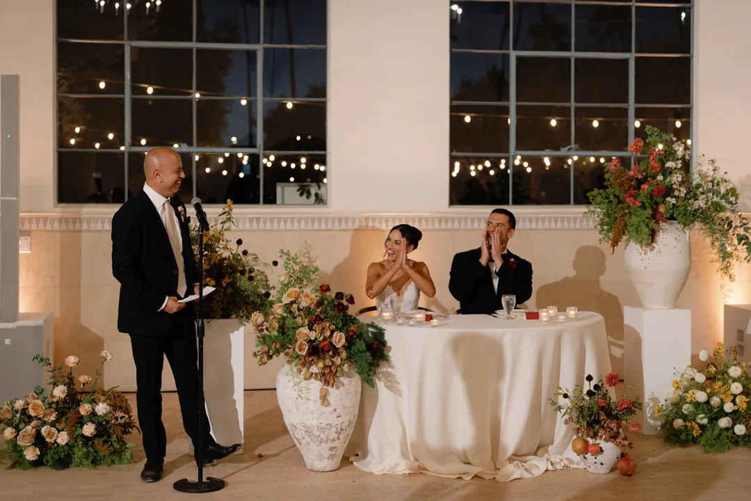 Guest giving a speech beside the seated couple