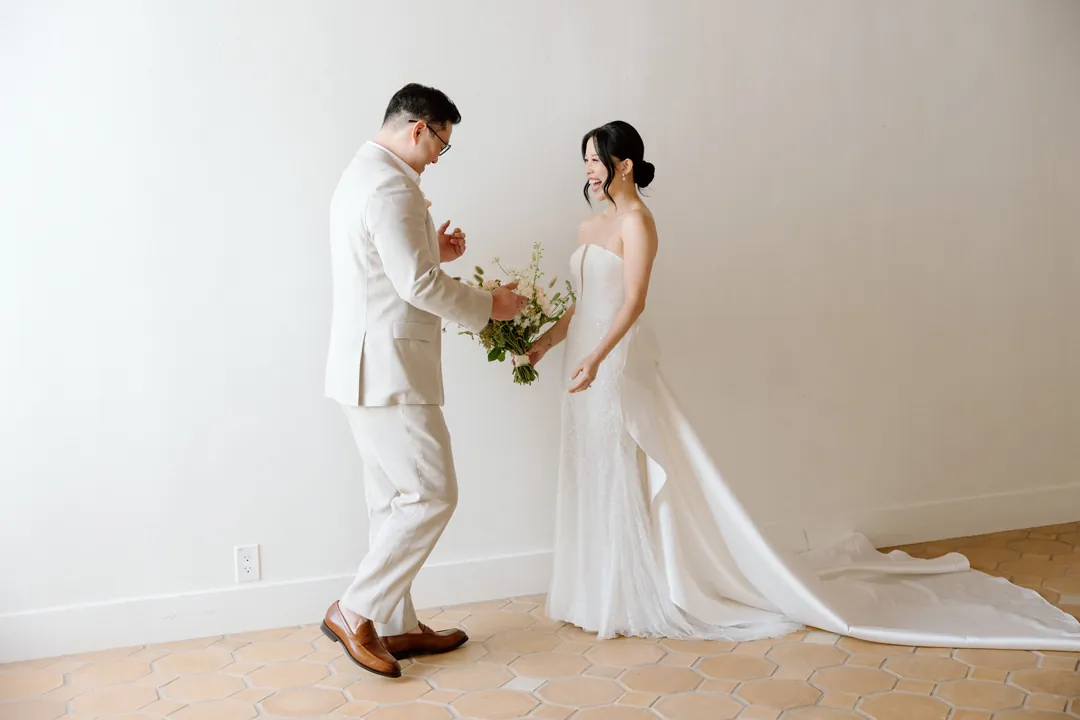 Bride and groom exchanging a gift in a bright room