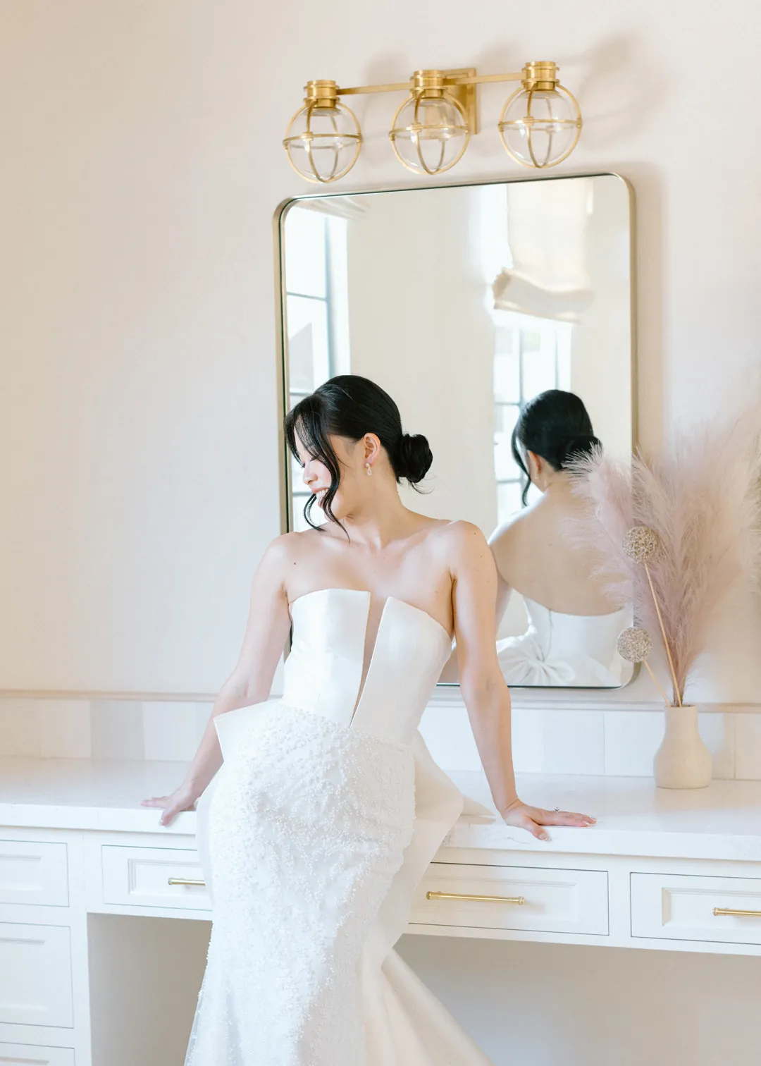 Bride seated at a mirrored dressing table