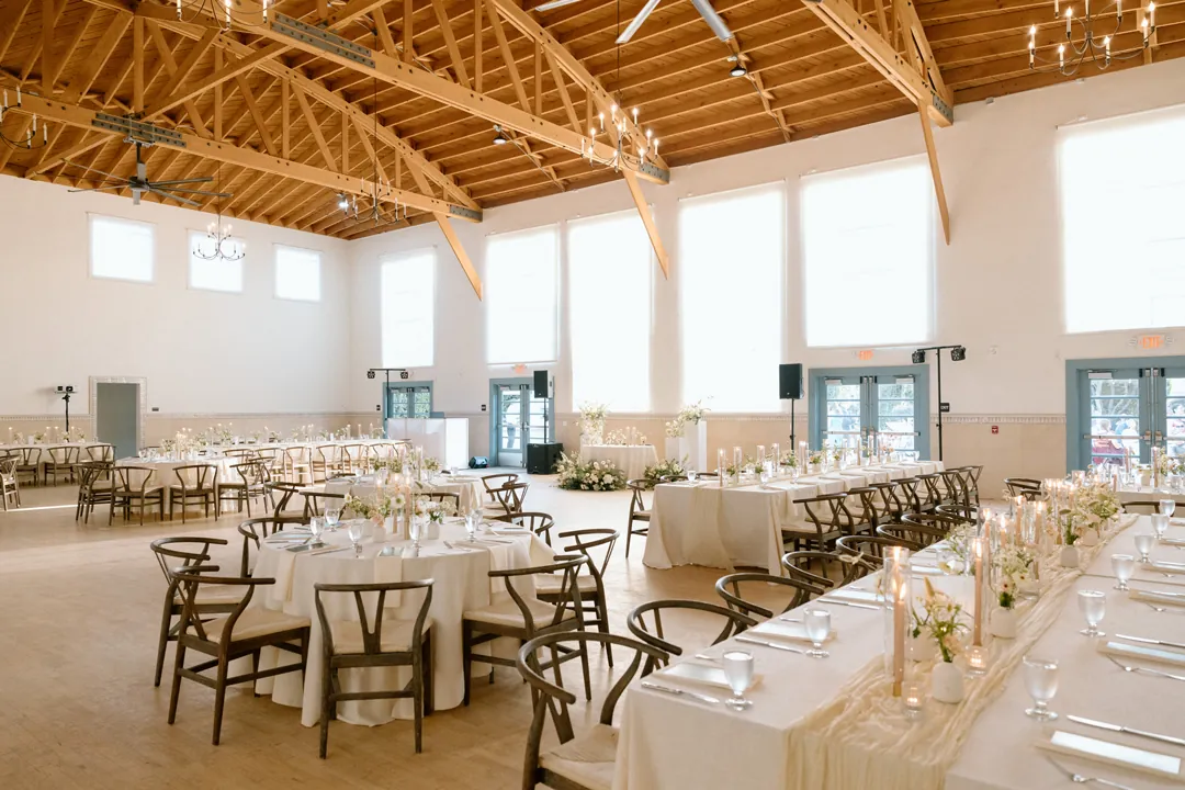 Reception tables beneath the bright wood-beamed ceiling
