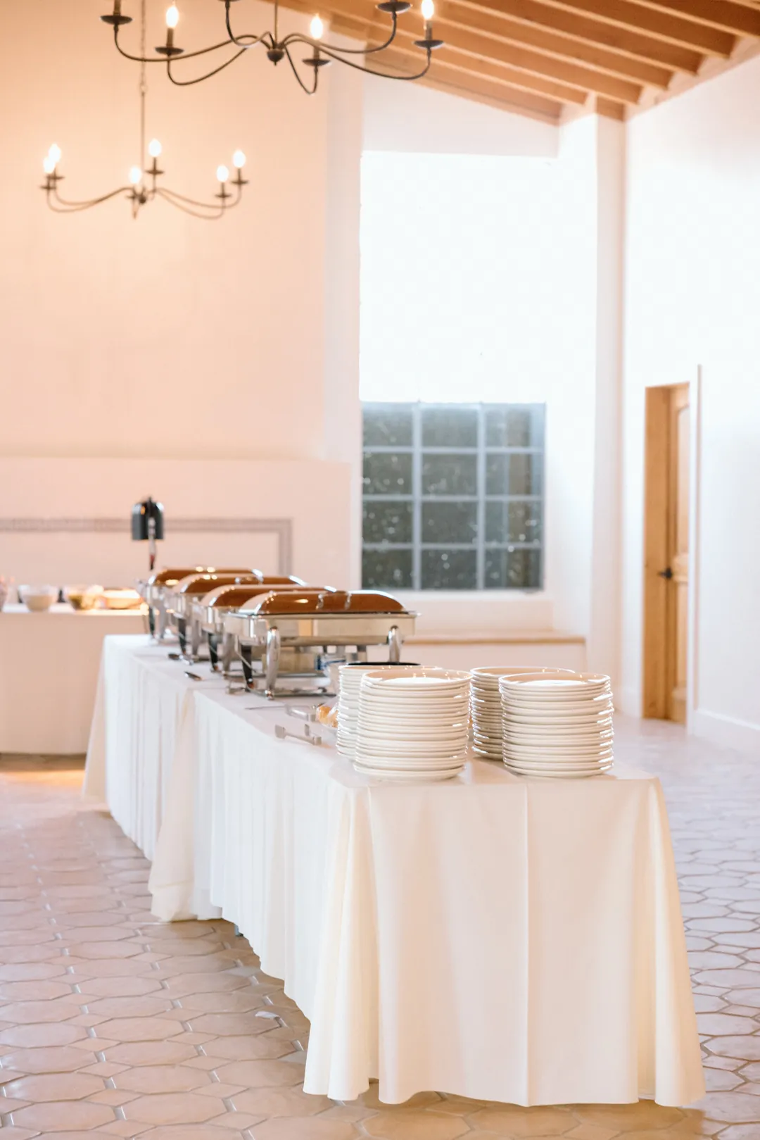 Buffet station with serving trays and stacked plates