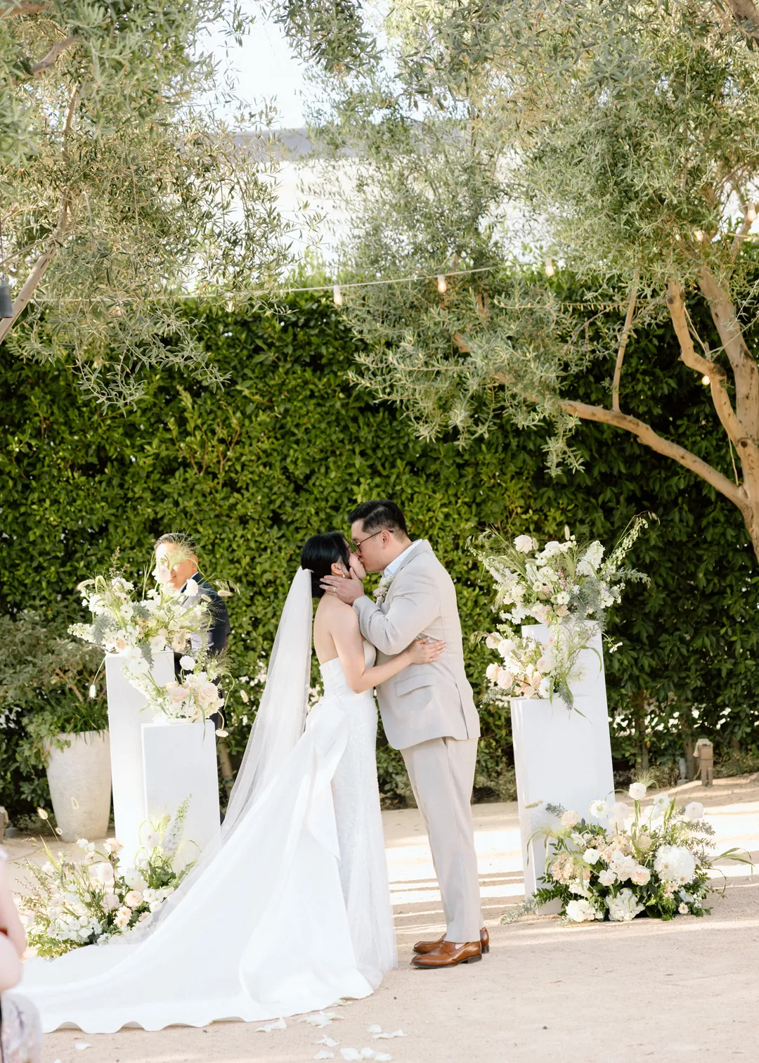 Bride and groom kissing among white flowers