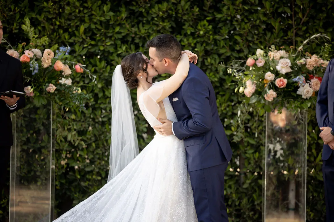 Bride and groom kissing beneath pink flowers
