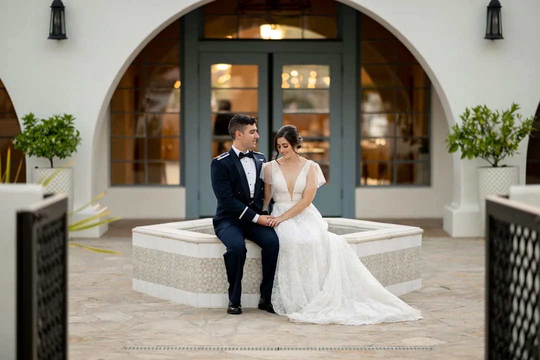 Bride and groom seated beside the courtyard fountain