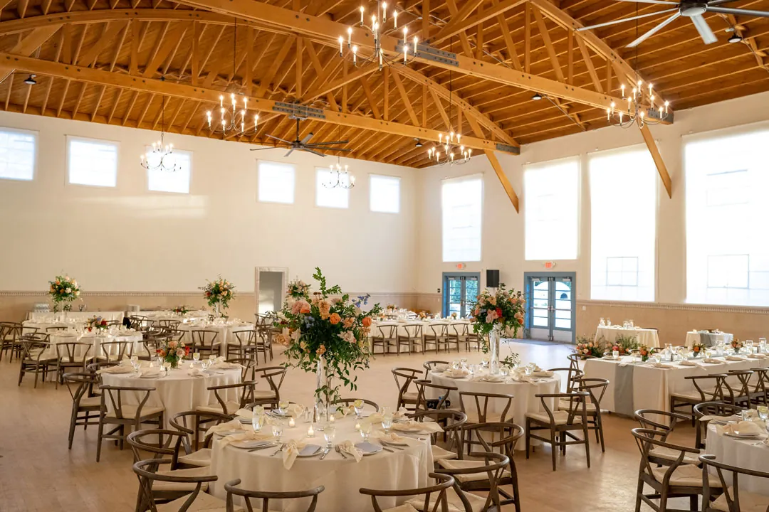 Reception tables beneath the bright wood-beamed ceiling