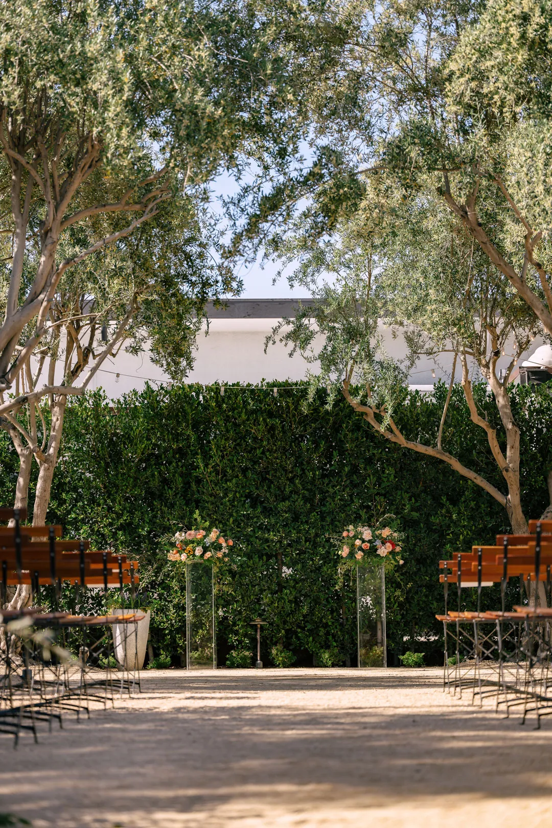 Floral ceremony backdrop beneath courtyard trees
