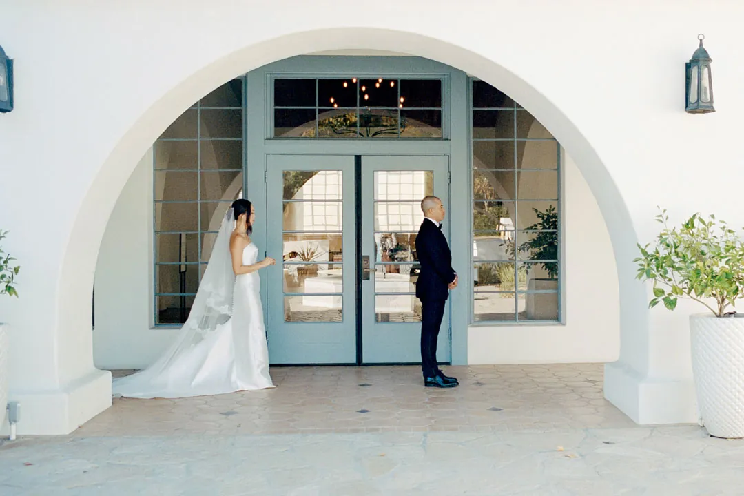 Bride approaching the groom beneath an exterior archway