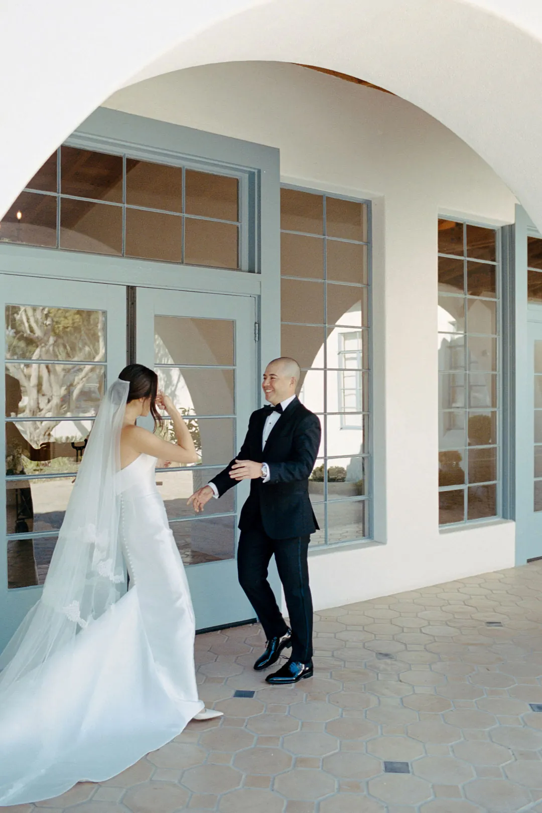 Bride and groom holding hands outside glass doors