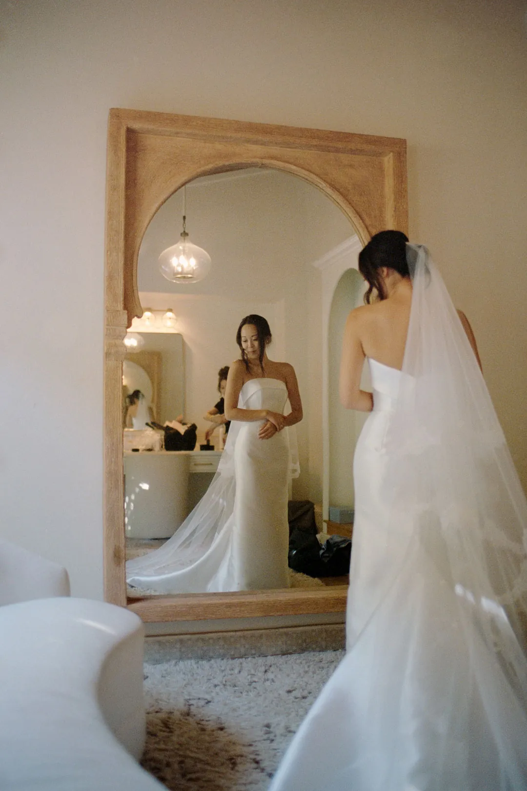 Bride reflected in a tall dressing-room mirror