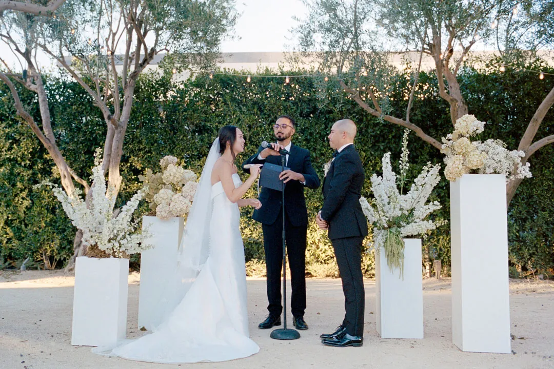 Officiant addressing the couple among white floral arrangements