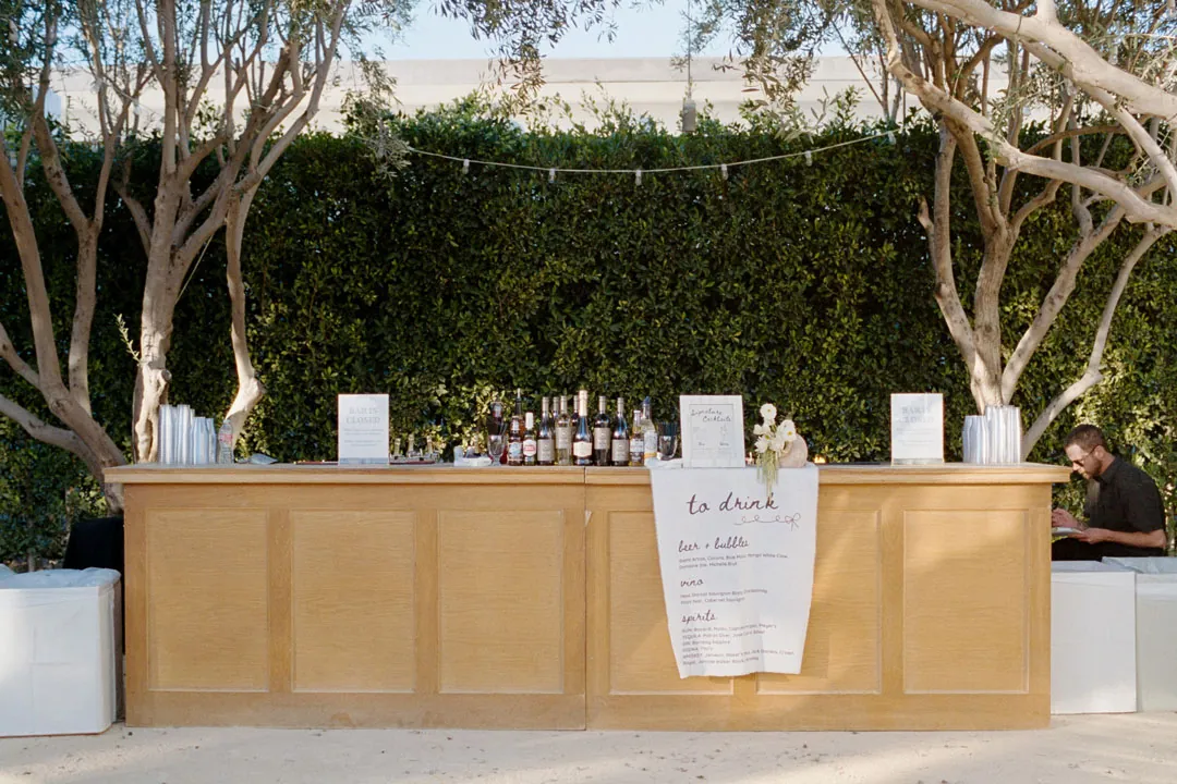Wooden outdoor bar with bottles and a drinks menu