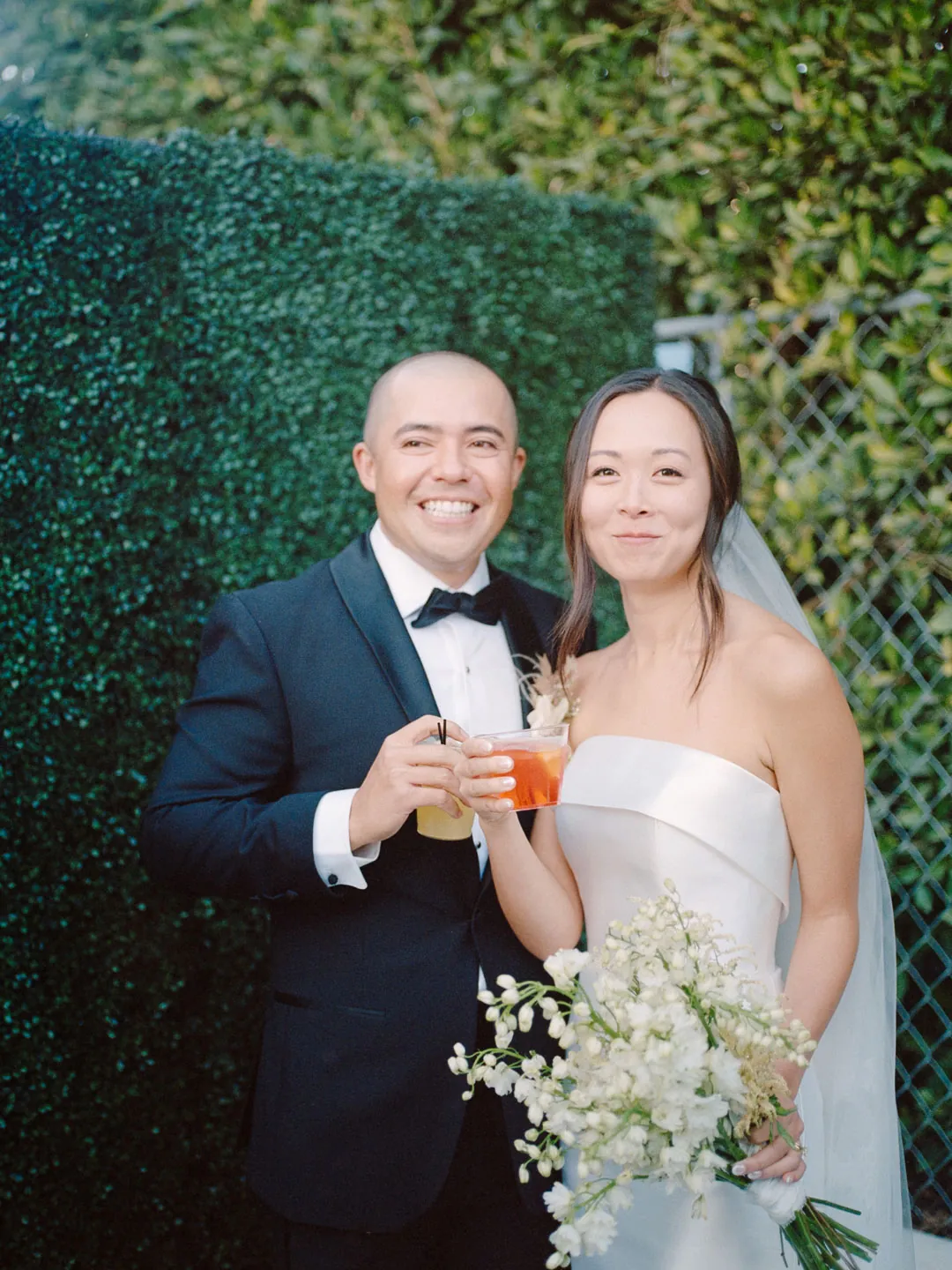 Bride and groom smiling together with drinks outdoors