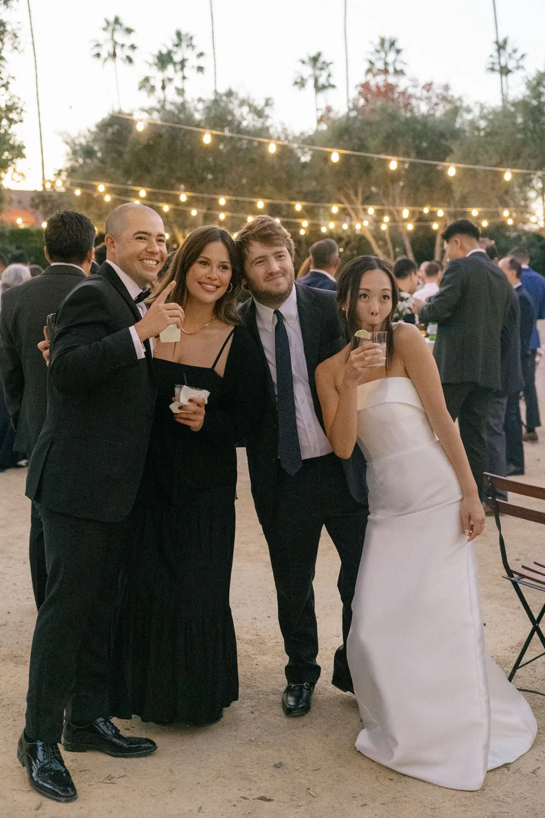 Wedding guests posing together beneath courtyard string lights