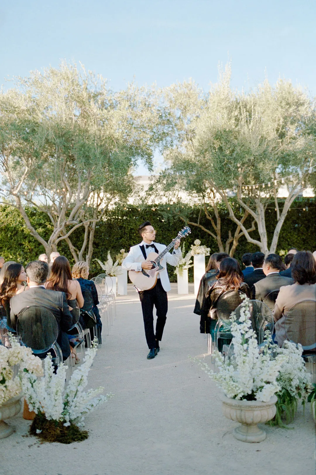 Groom walking along the ceremony aisle with a small dog