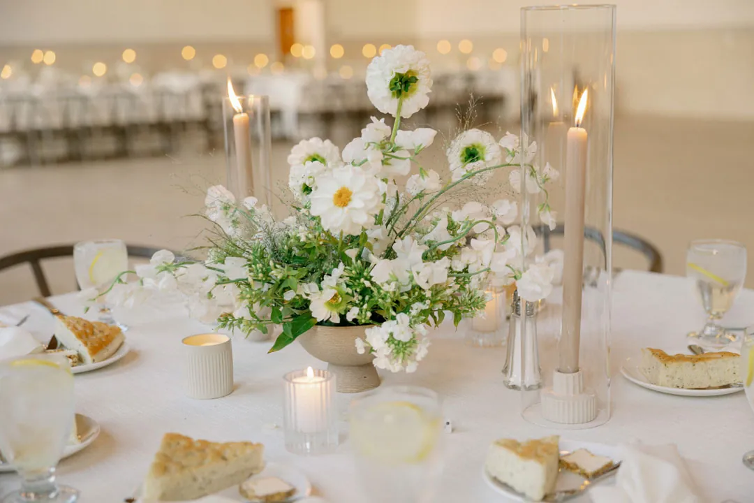 White and green floral centerpiece with candles and glassware