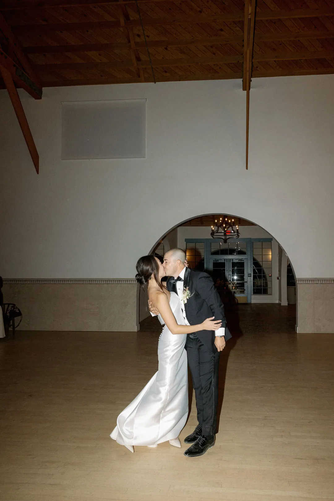 Bride and groom kissing inside the reception hall