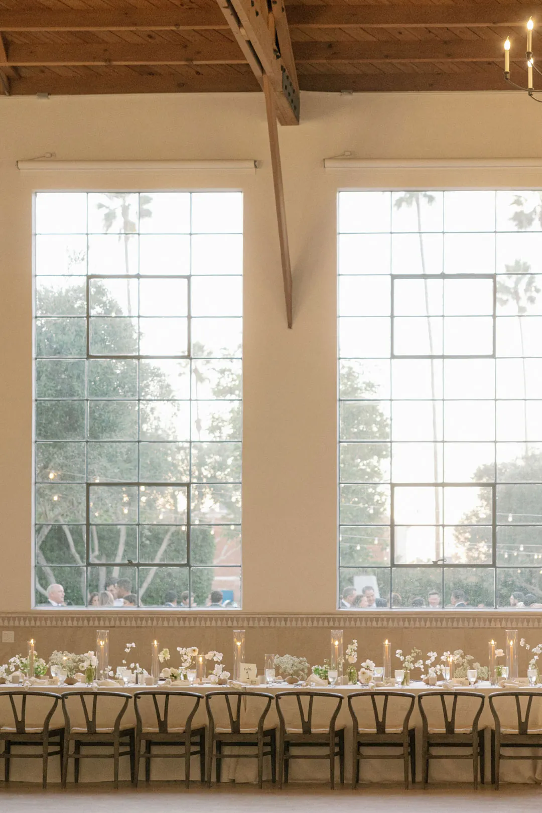 Long reception dining table beneath tall windows