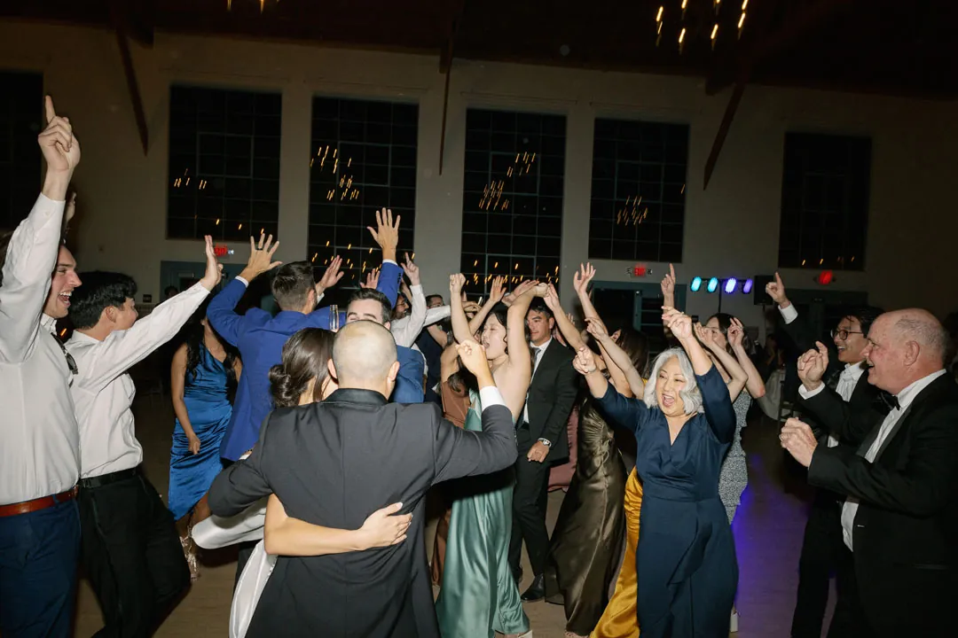Guests dancing together with raised arms during the evening reception.