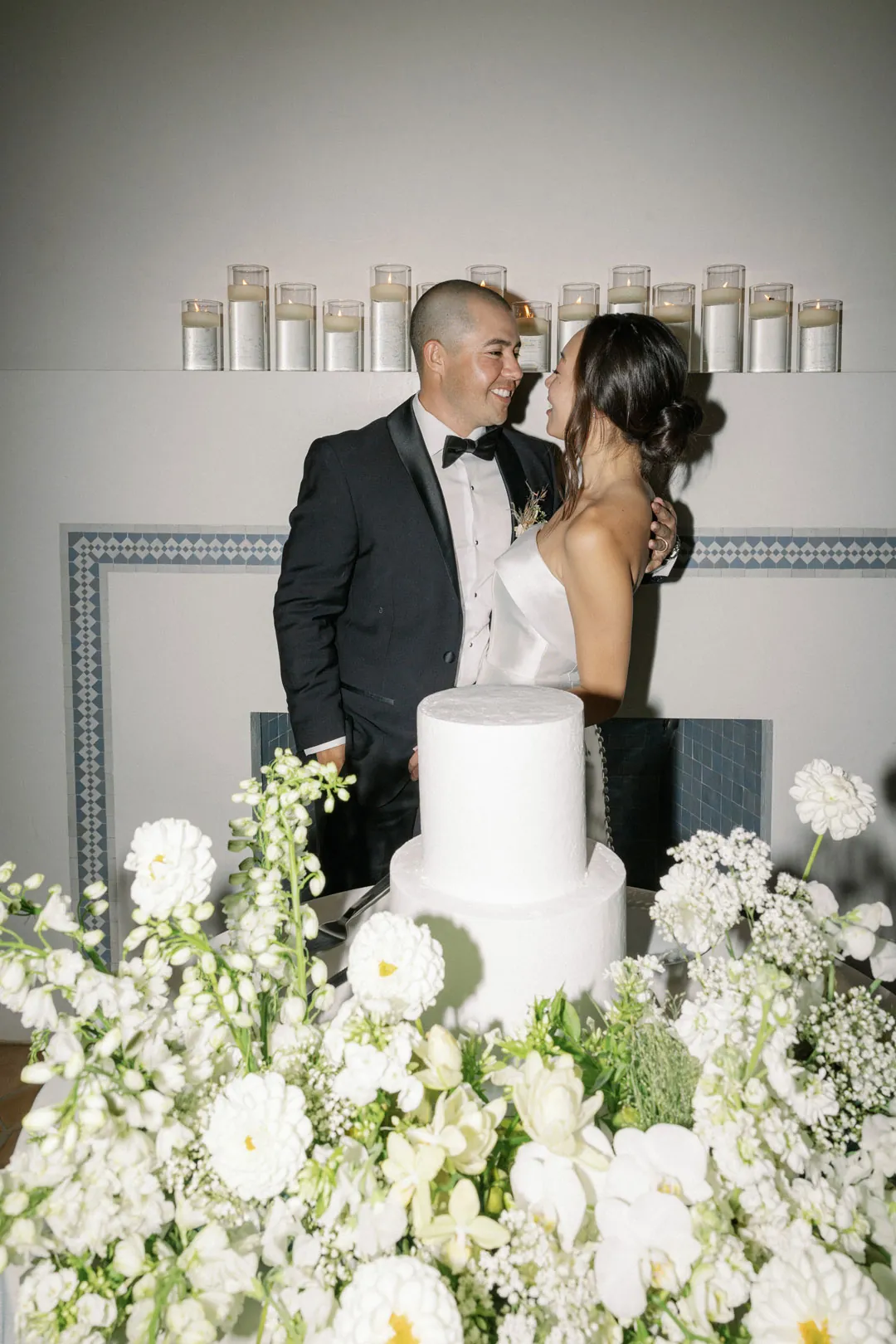 Newlyweds kissing behind their flower-covered cake table.