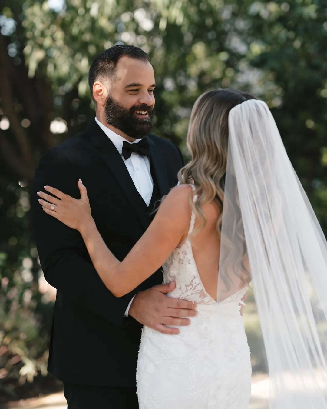 The couple embraces beneath courtyard olive trees.