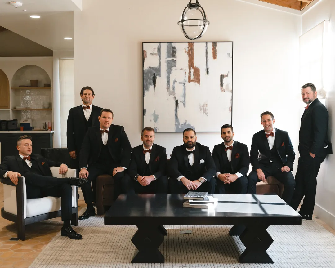 The groom and friends pose together around a lounge coffee table.