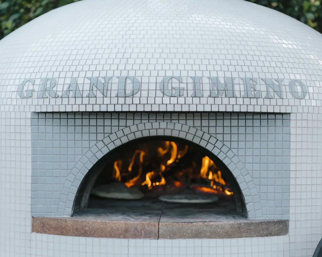 Flames burn inside the tiled wood-fired pizza oven.