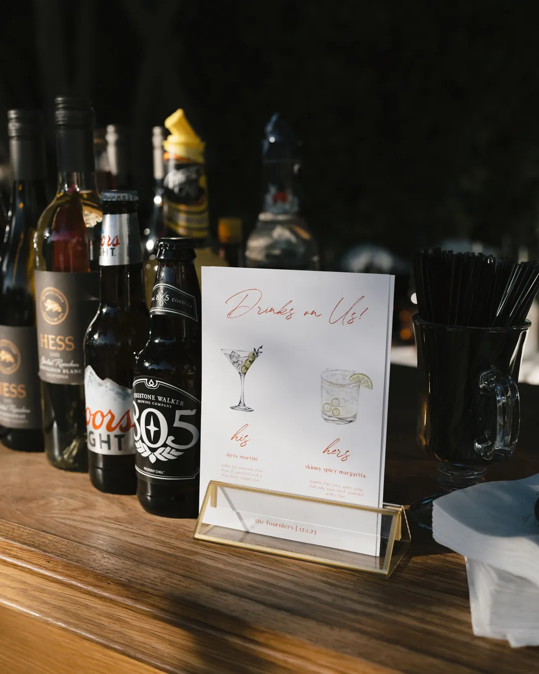 A printed drinks menu sits beside bottles on a wooden bar.